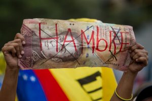 CAR01. CARACAS (VENEZUELA), 08/08/2015.- Una persona sostiene en su mano un billete de 100 bolívares fuertes falso, con la para "hambre" durante una manifestación hoy, sábado 8 de agosto de 2015, en la ciudad de Caracas (Venezuela). La alianza opositora venezolana Mesa de la Unidad Democrática (MUD) admitió que fue escasa la asistencia a la manifestación que convocó para hoy en Caracas, pero subrayó que ello no pone en dudas el triunfo que prevé en los comicios de diciembre. La convocatoria a marchar por todas las capitales de los 24 estados del país, y por zonas del centro-este de Caracas, "contra el hambre, contra el hampa por la libertad, por la unidad", finalmente reunió a unas pocas decenas de personas en una sola calle de la capital venezolana. EFE/MIGUEL GUTIERREZ