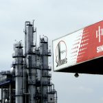 A Sinopec gas station stands in front of a Sinopec oil refin
