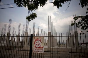 Una foto de Hugo Chávez cuelga de un cerco que rodea un proyecto de viviendas que no ha sido completado en Valencia, Venezuela, el 8 de abril del 2013. Las promesas incumplidas durante el gobierno de Chávez, la pobreza, apagones, la violencia, la inflación, la corrupción oficial y la escasez de alimentos podrían incidir en las elecciones presidenciales del domingo. (AP Photo/Ramón Espinosa).