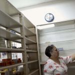 A pharmacy employee arranges medicines at a shelf in a drugstore in Caracas