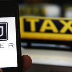 File illustration picture showing the logo of car-sharing service app Uber on a smartphone next to the picture of an official German taxi sign