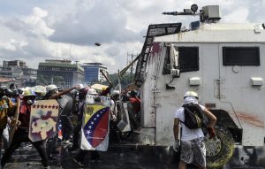 Opposition activists and riot police clash during a protest against President Nicolas Maduro in Caracas, on May 10, 2017. Venezuelan protesters hit the streets on Wednesday armed with "Poopootov cocktails," jars filled with excrement which they vowed to hurl at police as a wave of anti-government demonstrations turned dirty. / AFP PHOTO / JUAN BARRETO