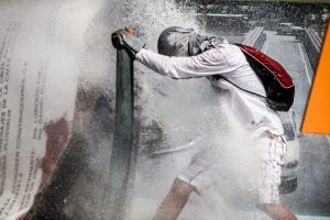 An opposition activist holds a makeshift shield to protect himself from the jet of a riot police water cannon during a protest against President Nicolas Maduro in Caracas, on May 26, 2017. Both the Venezuelan government and the opposition admit that violent protests that have gripped the country for nearly two months are out of control -- and analysts warn they could be a double-edged sword that might trigger even more unrest. / AFP PHOTO / FEDERICO PARRA