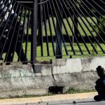 A member of the riot security forces points a gun through the fence of an air base at an opposition supporter during clashes at a rally against Venezuelan President Nicolas Maduro's government in Caracas