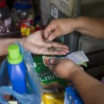 A customer receives his change back from a cashier at a supermarket in Caracas