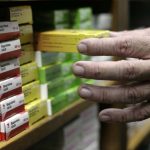 A pharmacist arranges boxes of medicine in a drugstore in Caracas