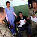 A patient listens while a US Navy Comfort Hospital ship staff doctor speaks outside of Divina Pastora High School in Riohacha