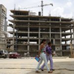 Women walk in front of a building under construction in Caracas