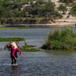 Asylum-seeking migrants cross the Rio Grande river in Del Rio