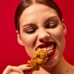 Young,Woman,With,Red,Lipstick,Eating,Fried,Chicken,,Nuggets,Over